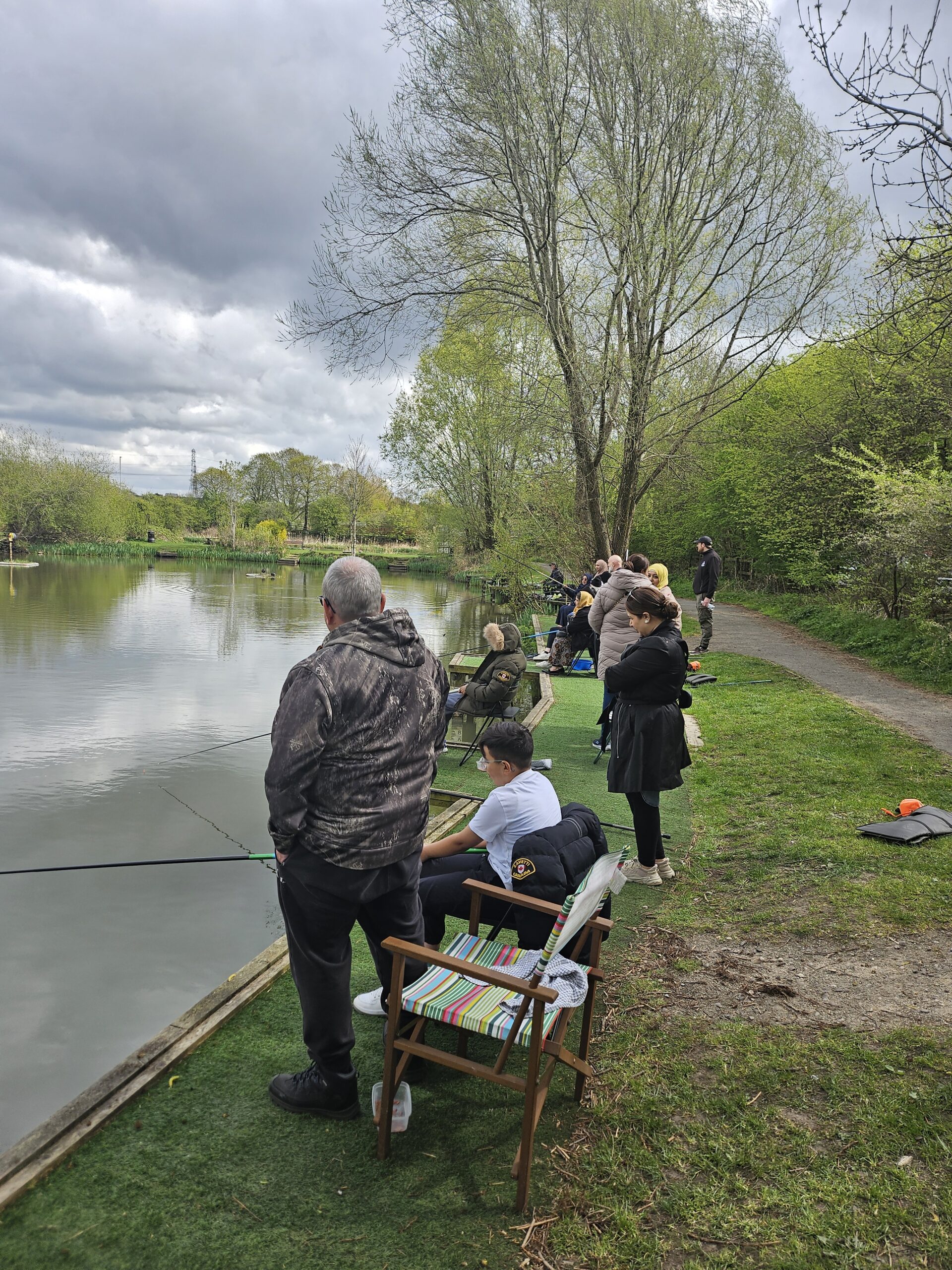 A slightly overcast day for fishing but the community group remains very keen to catch more fish and are gathered around the lake with their coach.