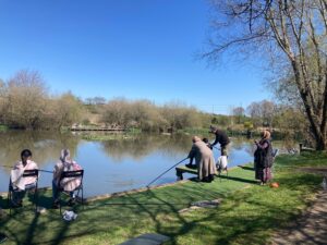 A serene scene of community group members from The BAME project in Bury enjoying nature and learning how to fish